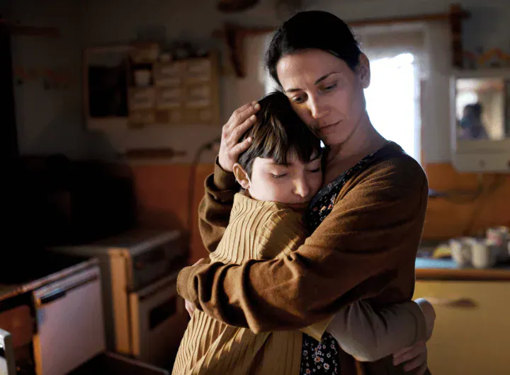 A mother hugs her small daughter at home