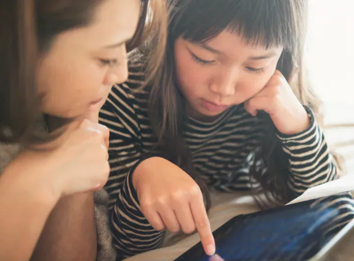 Mother and daughter playing with a digital tablet in bedroom