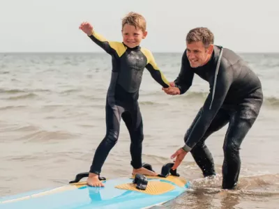 A dad helps a child surf