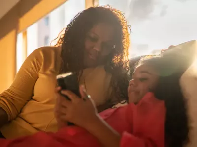 Mother and daughter using mobile phone at home